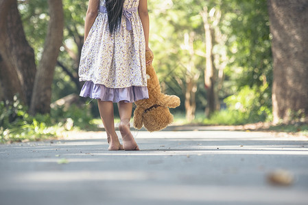 手拿泰迪熊的孤单女孩背影背景图片