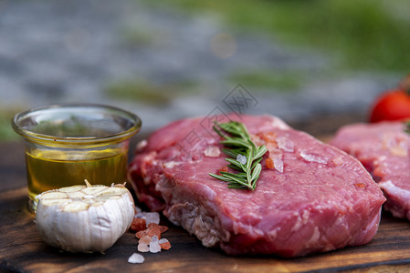 橄榄眼里脊肉煮熟的不在厨房木板餐桌背景上有迷迭香盐大蒜番茄黑辣椒橄榄油肉牛排和制品的木板上肉背景