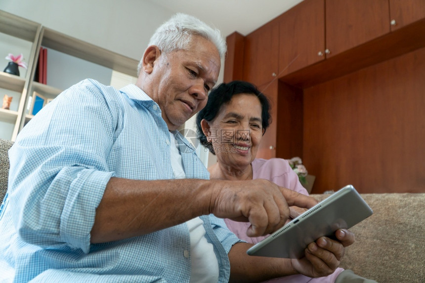 老的肖像外部快乐亚洲老年夫妇在假日季节使用平板电脑寻找度假目的地退休后快乐老年生活方式的概念图片