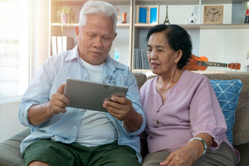已婚微笑成人快乐的亚洲老年夫妇在假日季节使用平板电脑寻找度假目的地退休后快乐老年生活方式的概念图片