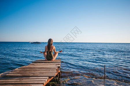 年轻的手日落漂亮的女人在码头上练习瑜伽年轻漂亮的女人在海滩上练习瑜伽图片