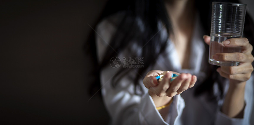 感染紧的亚洲妇女拿着药丸胶囊和年轻女手中的一杯水治疗卫生保健图片