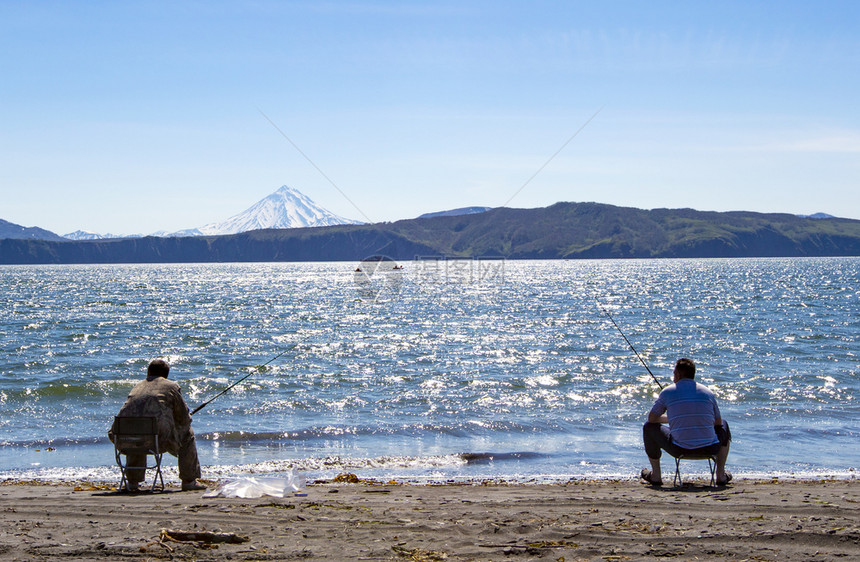 季节平静的在太洋海滩上坐着和捕鱼的渔捞员户外图片