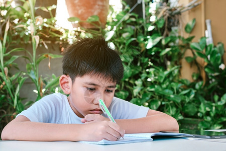 学生正在做功课的亚洲男孩用笔写记本亚洲人图片