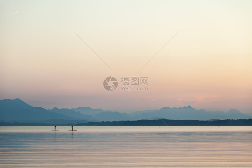 一对夫妇在湖边的日落时练习桨草一种冲浪登机图片