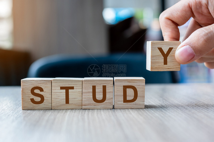实业家手握木立方块在表背景上用STUDDY的商业词写在表格背景上战略教研究图片