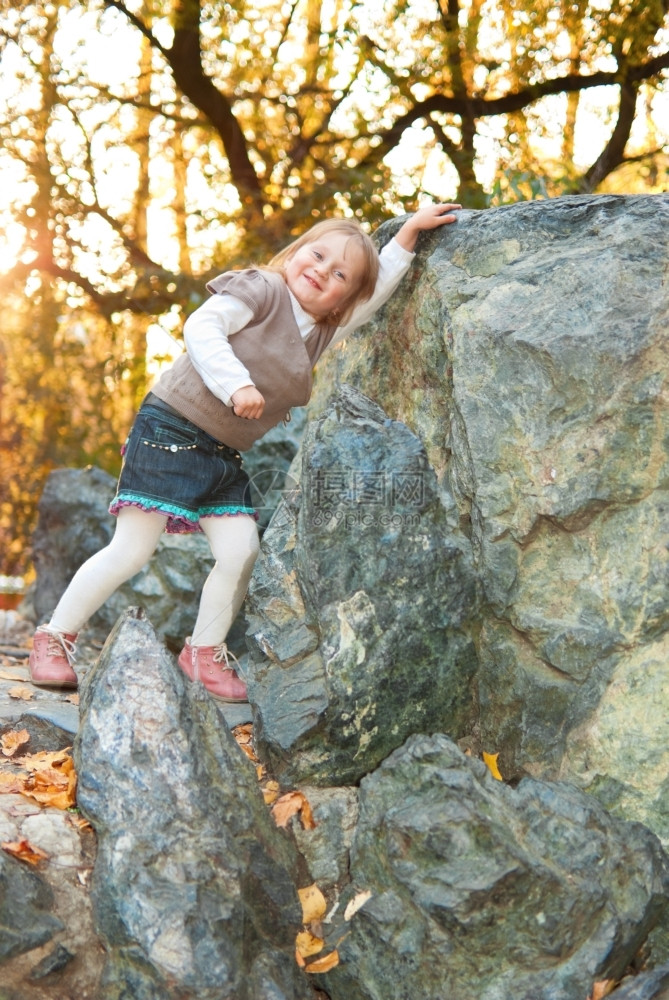 叶子树复制三岁的小女孩带着笑容的三岁小女孩仰着一块大石头她晚上在秋公园玩图片