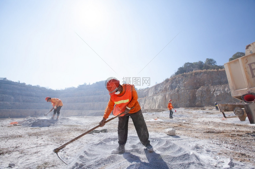 采石场安全挑战矿工与采具合作在灰尘和烘制热石矿太阳背景方面使用采矿工具图片