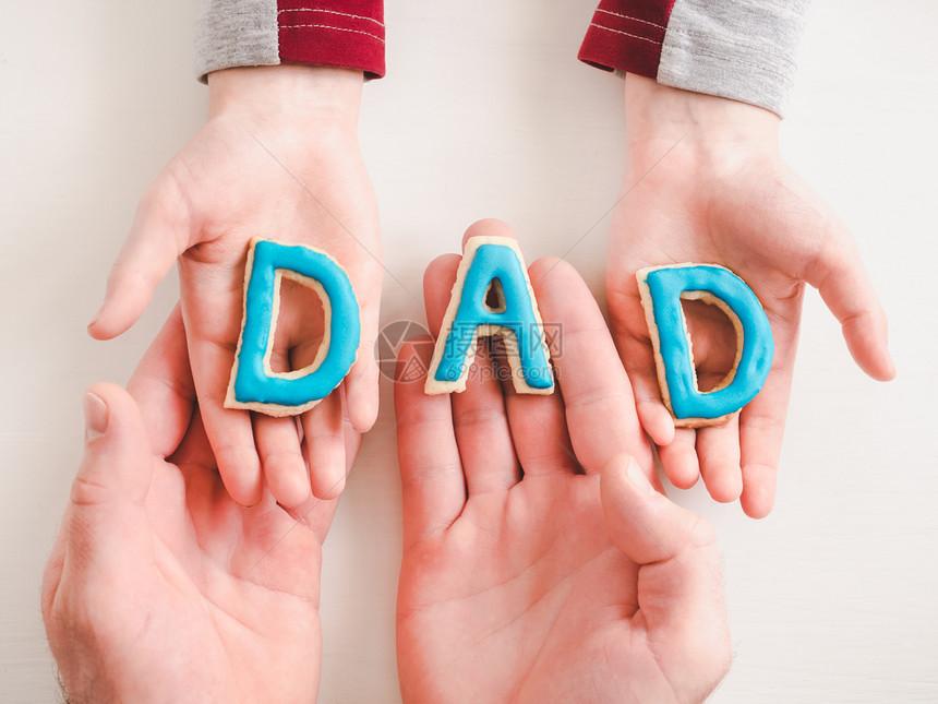 为了展示WordDAD由闪发光的饼干制成躺在孩子和她父亲的手掌上最接近高视野孤立的背景幸福家庭的概念女对平等日的美丽卡片木制图片