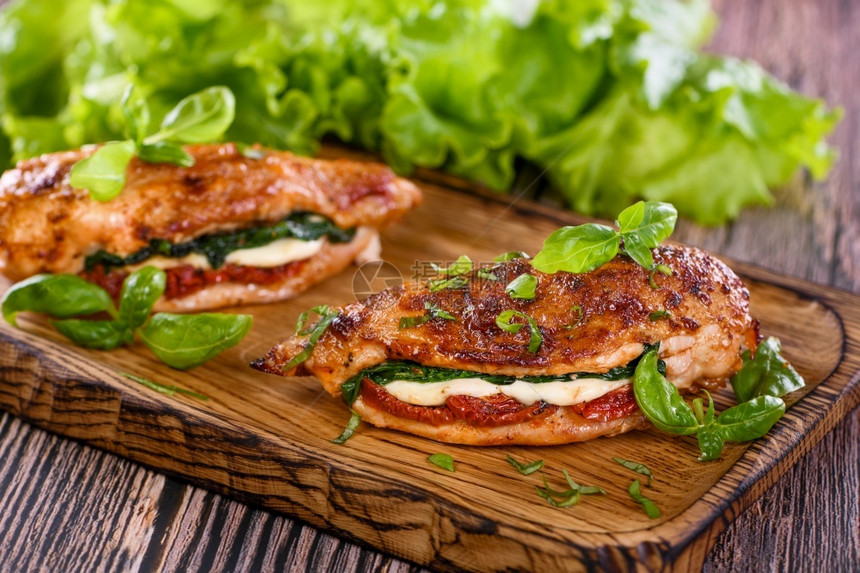 送达烧烤健康鸡胸包括马扎里拉晒番茄菠菜和肉用在木板上配有巴西和生菜图片