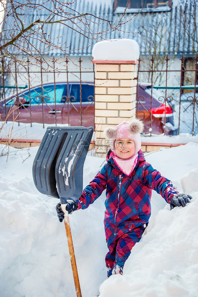 季节欢乐的女孩用铲子挖雪建造隧道冬季户外游戏欢乐女孩用铲子挖雪建设隧道夹克外部图片