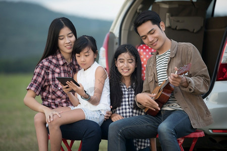 克里自由白种人快乐的小女孩与亚裔家庭一起玩乌鲁莱拉游戏坐在车里享受公路旅行和露营车暑假汽背景
