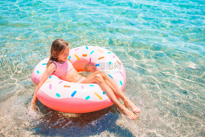 小女孩躺在泳圈里海中游泳图片