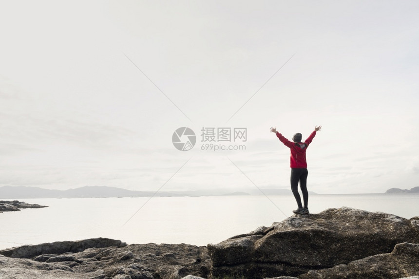 喜悦年轻的自然女人举起手来享受着美丽的海岸清晨风景图片