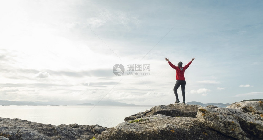 女人举起手来享受着美丽的海岸清晨风景地平线放松提高图片