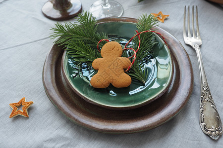 设置棕绿色古董板旧叉树枝和姜人灰色桌布和橙皮星的圣诞桌假期姜饼复古的图片