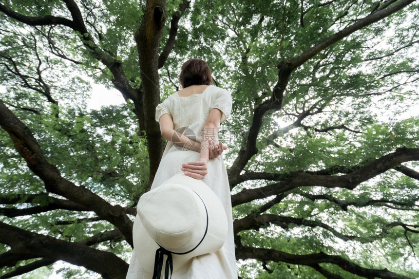 身穿白裙子的女人站在树下图片