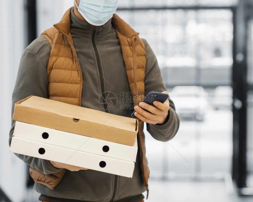 面具带罩的送货员拿着包裹快关门产品在线的图片