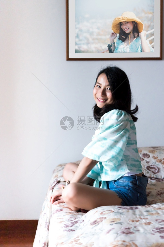 亚洲美女短牛仔裤独自坐在卧室的床上带着快乐和喜悦的情感在概念上充满欢乐的感觉快人生中的趣幸福和快的床上女人在感的枕头家图片