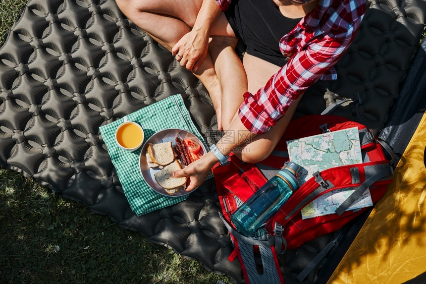 运动远足在露营地帐篷旁坐着早餐的妇女积极在靠近自然户外的地方过暑假难民营生活概念女积极度暑假乐趣图片