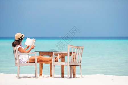 海滩上读书享受暑假年轻女子图片