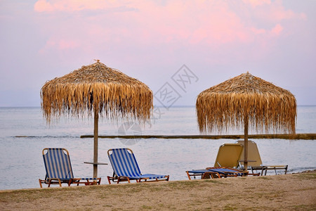 蓝色的海岸线美丽清晨海边滩的日落阳伞和甲板椅放松图片