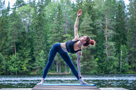 钜惠有礼海报身体灵活Yogi女孩练习瑜伽做UtthitaTrikonasana运动延伸三角形在湖上摆姿势放松背景