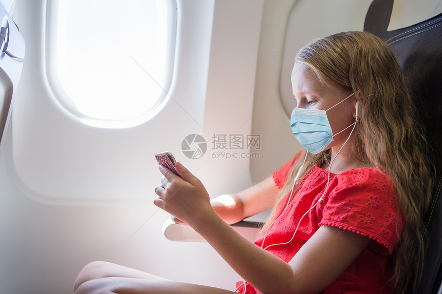人们玩闲暇身戴外科面具的小女孩临保护由飞机进行保护防止Corona和牵着手的小姑娘乘飞机旅行可随身携带外科面罩的小女孩图片