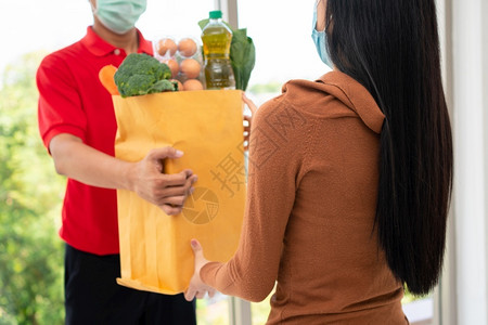 来自超市的亚洲送货员身戴面罩持有一袋新鲜食品蔬菜和水果供家里顾客使用特快杂货服务和新生活方式概念服务与新生活方式邮递员信使为了背景图片