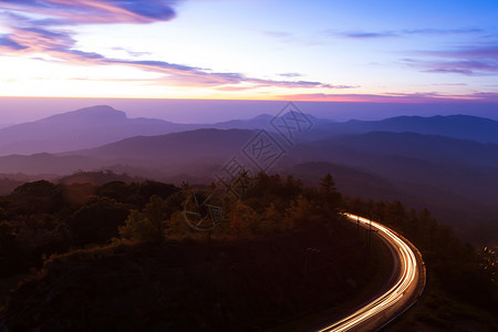 风起时黎明时的美丽山路天亮时美丽的山路有光向日出月空的卷曲山路背景运动驾驶村庄设计图片