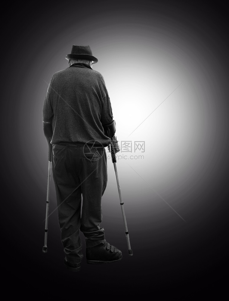 麻痹用两根拐杖从黑暗中向着光环移动微笑的上士残疾人病图片
