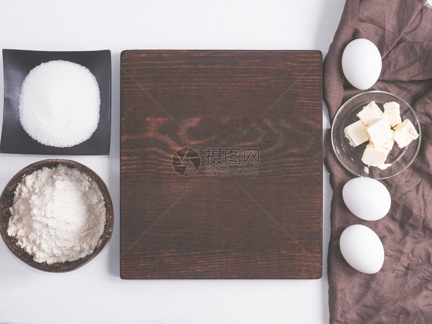 碗木板面粉糖鸡蛋黄油等自制食物的成份花粉黄油放在一个美丽的古老反面板上桌图片