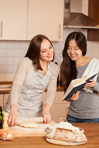 乐趣准备女人在赚钱而她朋友在看烹饪书时生的图片