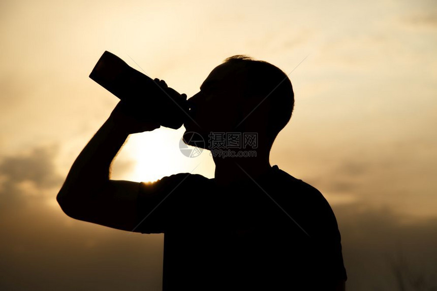 身穿黑色T恤和短裤的白人体育青年男子在日落时喝瓶酒饮用水的肖像休息白种人慢跑图片