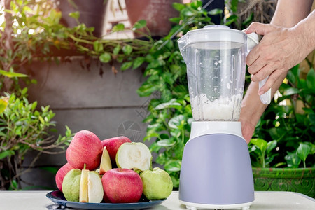 人们的手在用电搅拌机来制造新鲜苹果和瓜瓦汁烹饪混合器自然图片