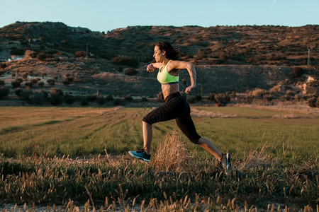 自由关心女跑步者在春草林中自然界的锻炼运动爬坡道图片