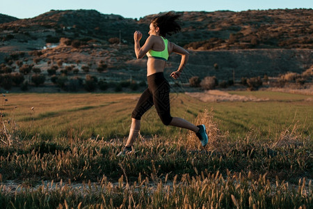 活力快乐的女跑步者在春草林中自然界的锻炼运动积极图片