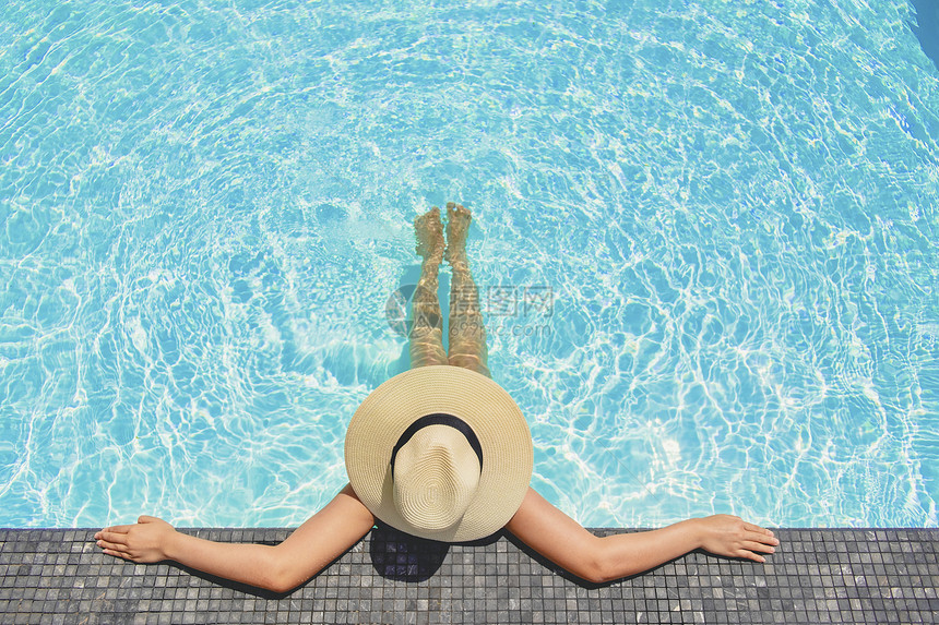 泳装女人戴着大帽子在泳池放松图片