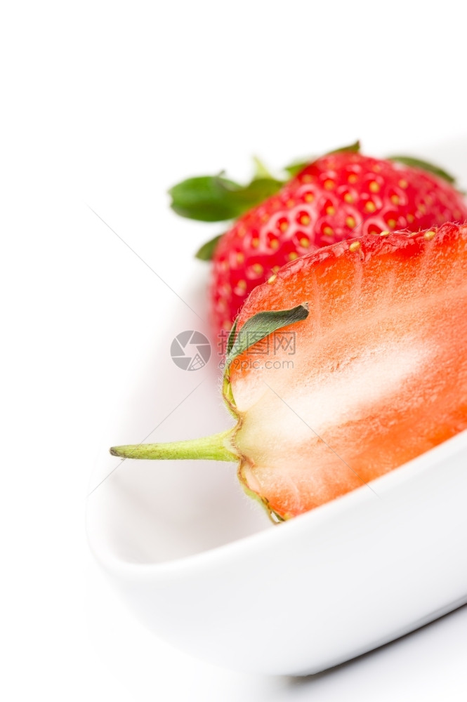 甜美食物在一个白色陶瓷碗中用一个半熟新鲜的成草莓肉汁丰盛的鲜熟草莓用于烹饪和烘烤作为富含维生素C的健康成份为了图片
