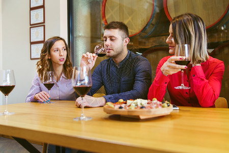 红酒杯经过在室内桌边一家人年轻的白男女妈坐在桌边喝红酒兄妹在家聊天图片