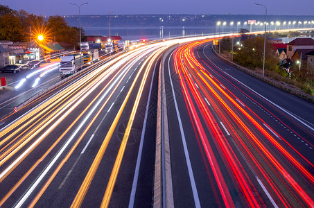 汽车尾喉运输郊区的夜间高速公路车头灯和尾的痕迹交通繁忙的尾灯和公路上晚间汽车与铁轨交和卡泊桥的灯光天空背景