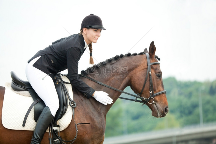 运动坦率休闲的穿着西装和头盔的快乐女青年骑马并穿行其颈部图片