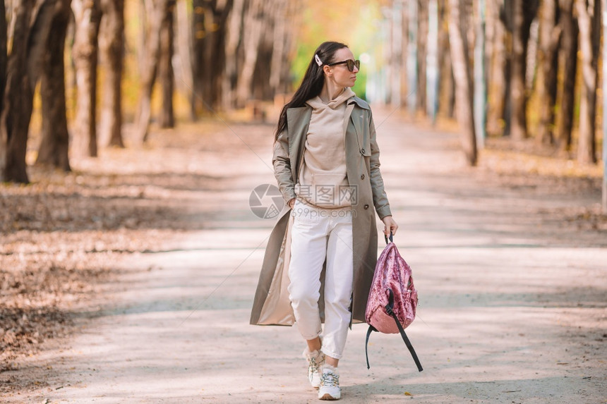 女孩杯子秋天公园中穿着棕色大衣的女人在秋天金色日公园Fall概念下美丽的女人在秋天公园里喝咖啡图片