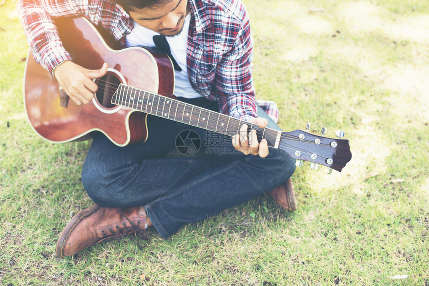 年轻的嬉皮士在公园里练习吉他快乐和享受p年轻的嬉皮士在公园里练习吉他快乐并喜欢弹吉他草地木板外部图片
