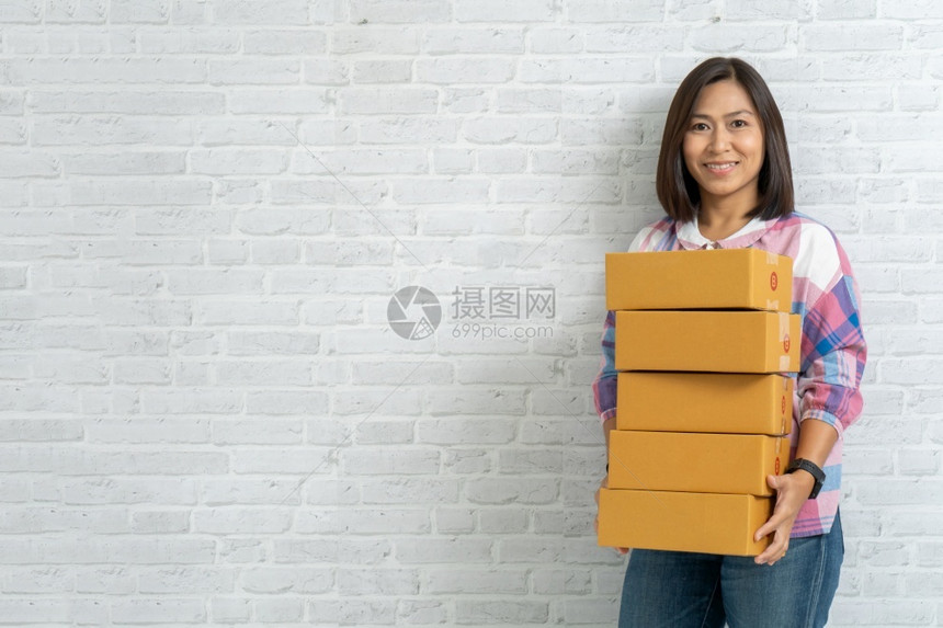 人们年轻的亚洲妇女携带棕色包裹或纸板盒在砖墙背景上子图片