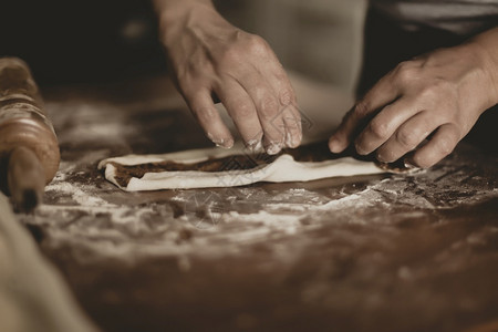 女士在土耳其妇女用塑料手套在桌子上做面团的手工制作烘烤图片