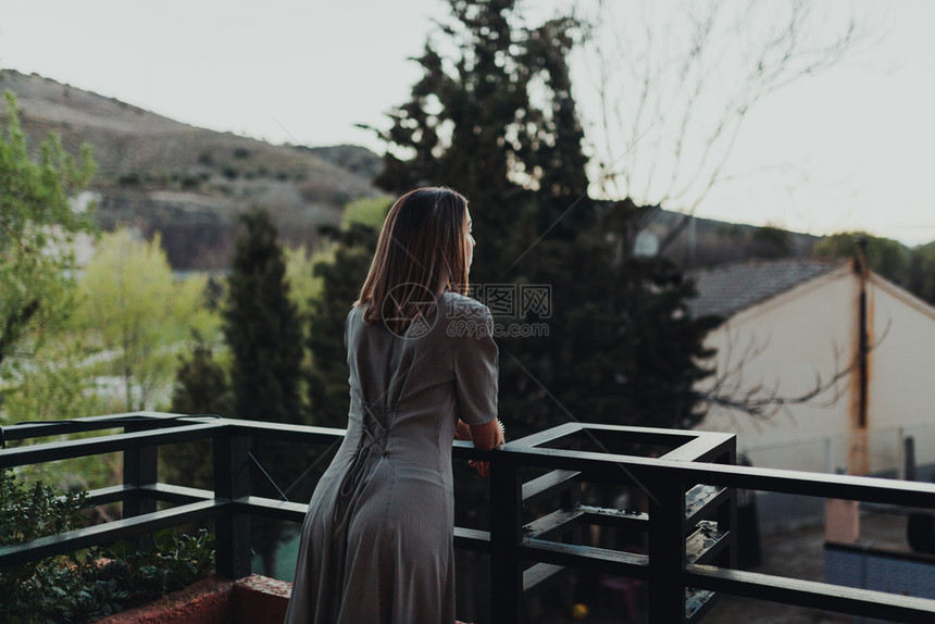 小屋花园年轻的天主教女青年从阳台上看日落休息图片