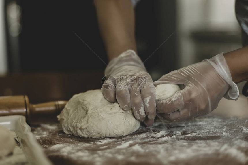 在土耳其妇女用塑料手套在桌子上做面团的手意大利烤房松紧带图片