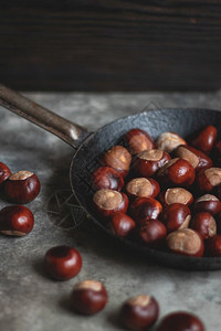 贝壳食用棕色的餐桌上一个旧铁锅的红栗子在旧铁锅上的红栗子图片