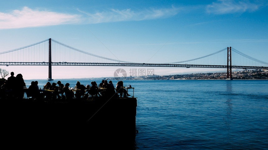 欧洲人们在户外餐厅露台上放松的剪影俯瞰葡萄牙里斯本标志4月25日桥人们在户外餐厅露台上放松的剪影俯瞰葡萄牙里斯本标志日桥四月禅图片